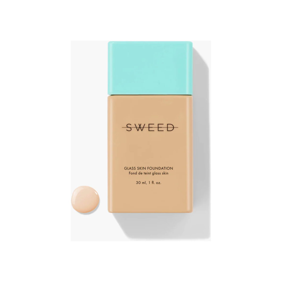 Bottle of foundation with a drop of its content next to it on a white background.