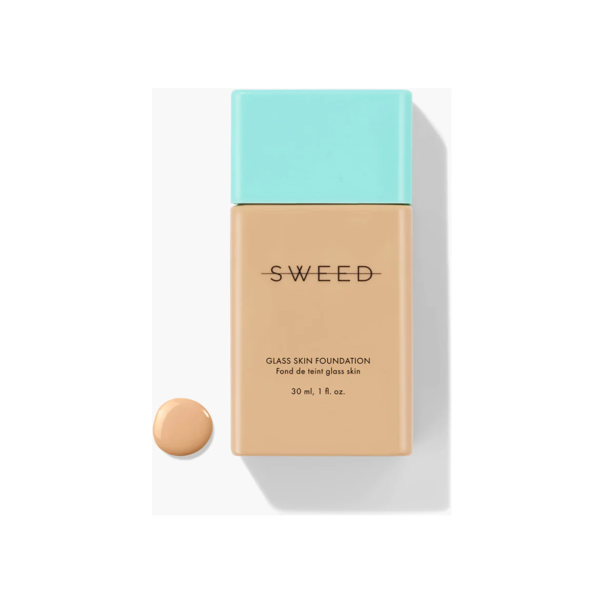 Bottle of liquid foundation with a sample dab of product beside it on a white background.