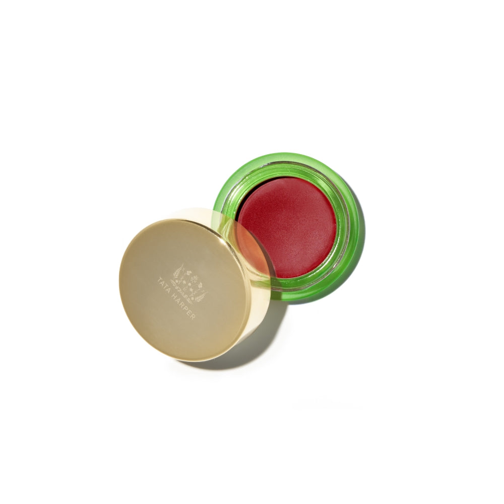 Open container of red lip balm with a gold-colored lid, isolated on a white background.